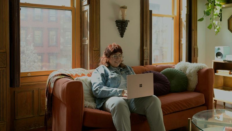 Frau entspannt mit Laptop auf dem Sofa, um im Casino kostenlos spielen zu testen