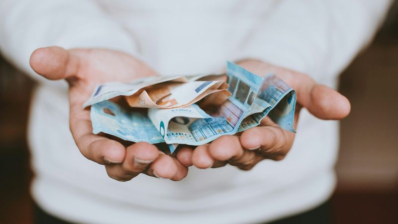 Hände halten zerknüllte Euroscheine, echtes Geld wie beim Online Casino Echtgeld