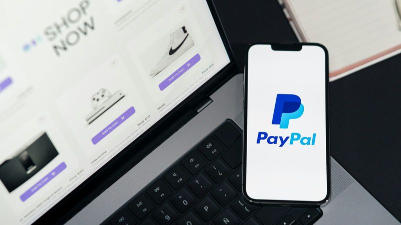 Smartphone mit PayPal-Logo auf dem Laptop, bezahlen im Online Casino PayPal